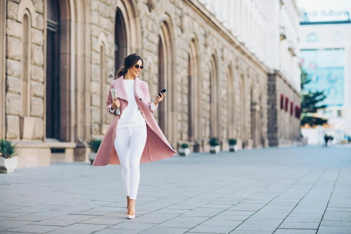 Eine elegante junge Frau ist trendy gekleidet und läuft eine Straße entlang.