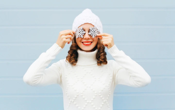 Strickpullover können mit grobem oder feinem Strick getragen werden und sind ein stylisher Winterbegleiter. Hier ist eine junge Frau in weißem Strickpullover mit passender Strickmütze zu sehen.