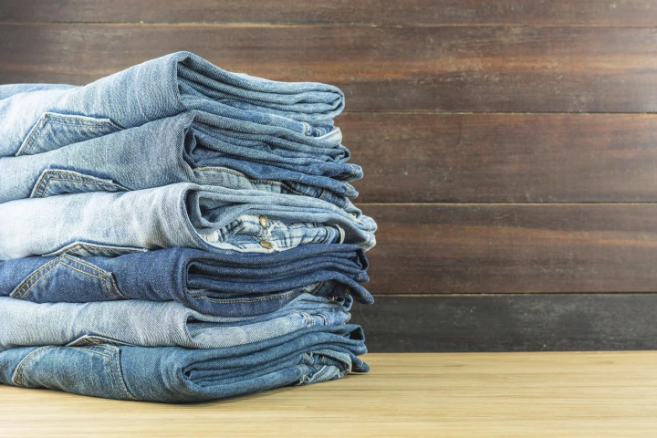 Greifen Sie zur Jeans! Mit diesem trendigen Kleidungsstück machen Sie nichts falsch. Hier ist ein Stapel aus sechs gefalteten Jeans abgebildet.