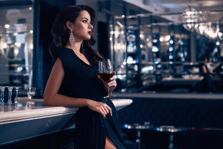 Stilvolle Frau in elegantem Kleid mit einem Glas Wein in der Hand
