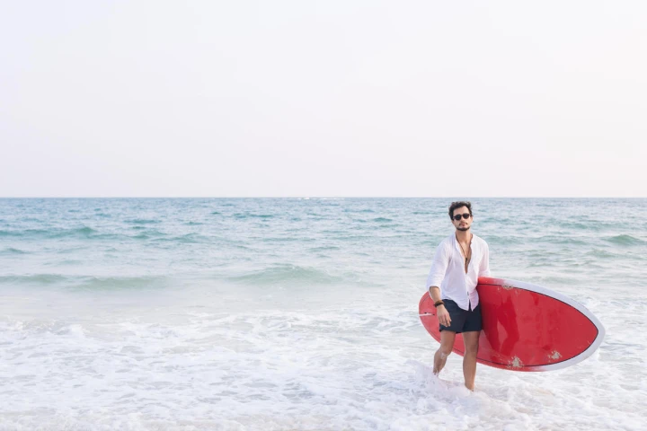 Mann mit rotem Surfbrett in Bermudas