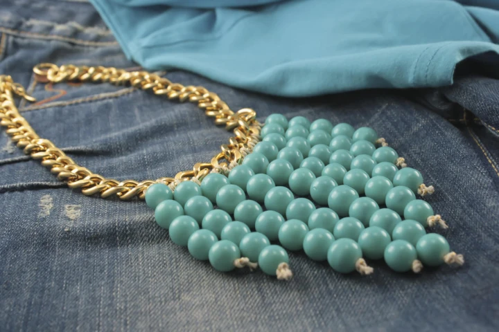 Ein Statement oder Unterstatement kann auch mit Schmuck gesetzt werden, zum Beispiel mit einer großen und auffälligen Kette. goldene Statement-Kette mit grünen Perlen