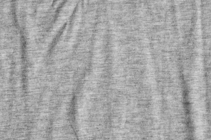 Jersey ist ein Stoff, der sich auf der Haut sehr angenehm anfühlt und deshalb in den meisten Basic-Kleidungsstücken verarbeitet wird. Grauer Jerseystoff, der leichte Falten wirft