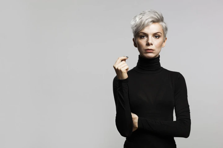 Model mit kurzen grauen Haaren trägt einen schwarzen eng anliegenden Rollkragenpullover