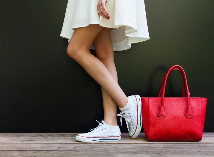 Weiße Sneaker neben roter Handtasche