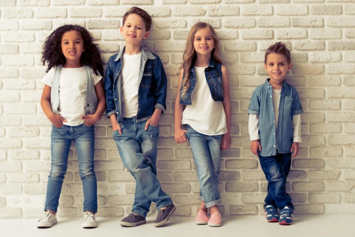 Vier Kinder tragen verschiedene Outfits aus dem Stoff Denim.