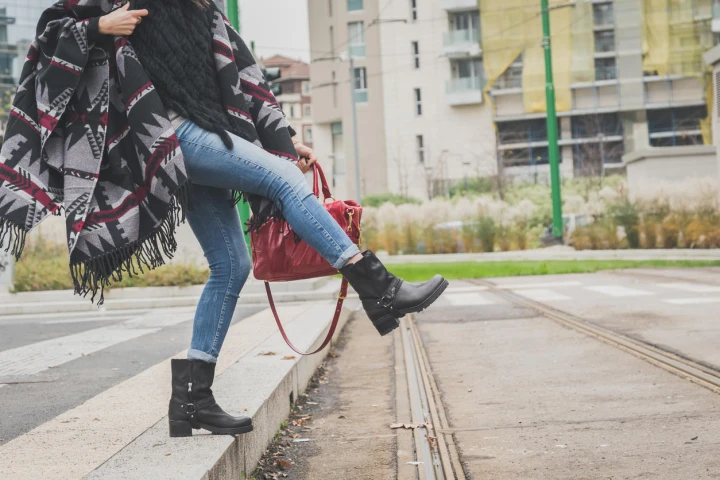 Junge Frau mit schwarzen Biker Boots und Poncho