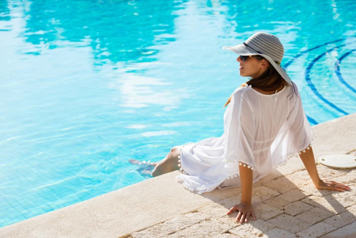 Frau im weißen Kaftan mit Sonnenbrille und Sonnenhut