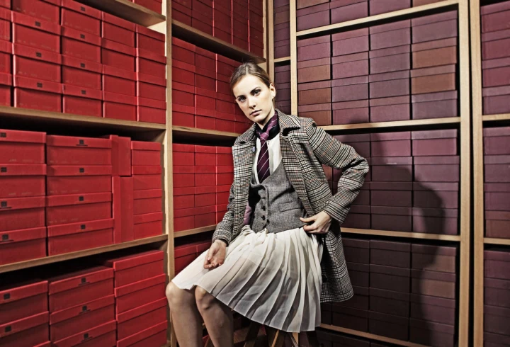 Junge Frau sitzt auf einem Hocker und trägt Kleidung aus Donegal Tweed. 