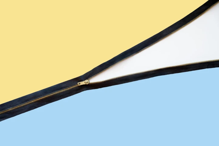 Halb geöffneter Zipper zwischen gelbem und blauem Stoff