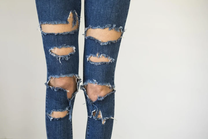 Eine Frau trägt eine blaue Jeans mit mehreren Cut-Outs
