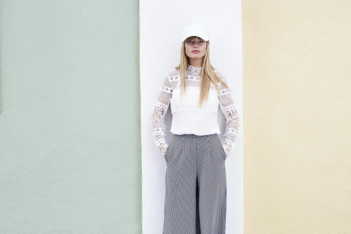 Der trendige Hosenrock ist eigentlich eine Hose, doch sieht er einem Rock sehr ähnlich. Die perfekte Alternative wenn man sich zwischen Rock und Hose nicht entscheiden kann! Frau in weißem Oberteil mit viel Spitze und einem grauen Hosenrock.